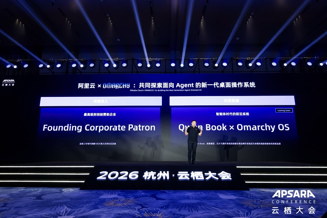 2026년 항저우 Apsara Conference 무대에서 Alibaba Cloud의 Founding Corporate Patron 후원 약속과 Omarchy와의 Qwen Book 협력을 발표하는 모습.